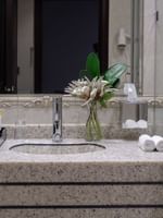 Granite sink with flower vase by a mirror and toiletries a bathroom in Standard Room at Warwick Al Jubail