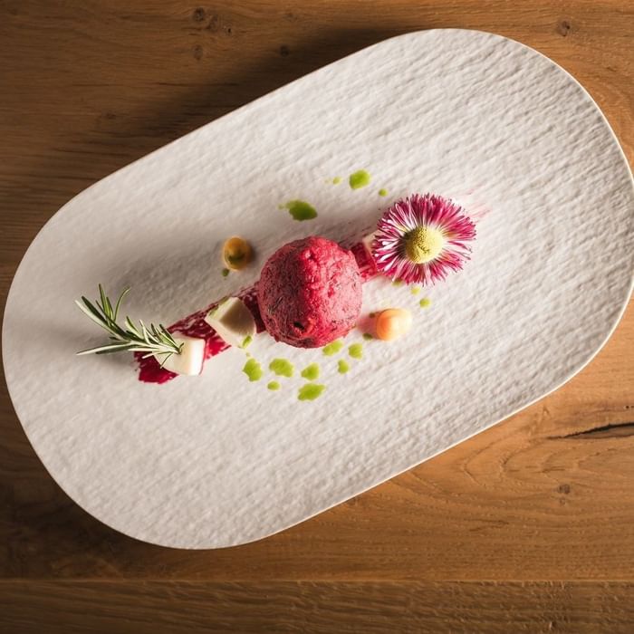 Rote Kugel mit Blatt und Blume auf einem weißen Teller bei Falkensteiner Hotel Falkensteinerhof