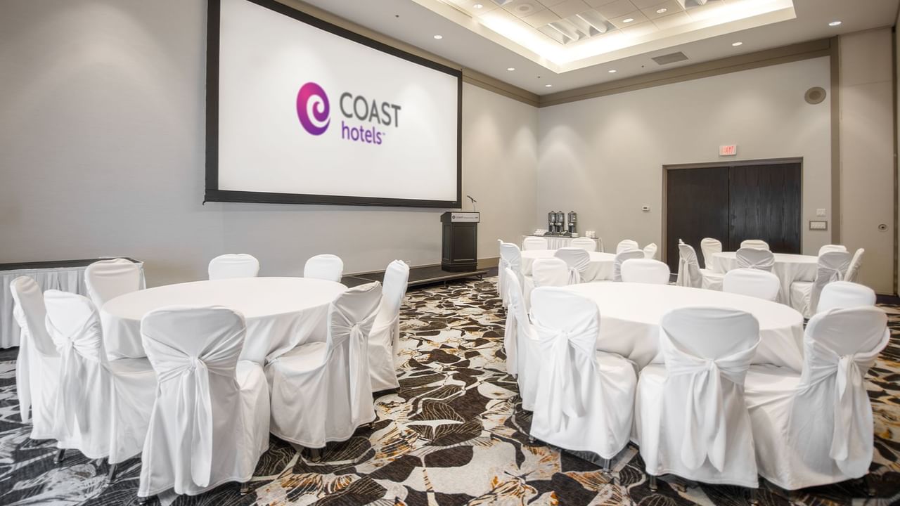 Banquet room with white-covered tables and chairs.