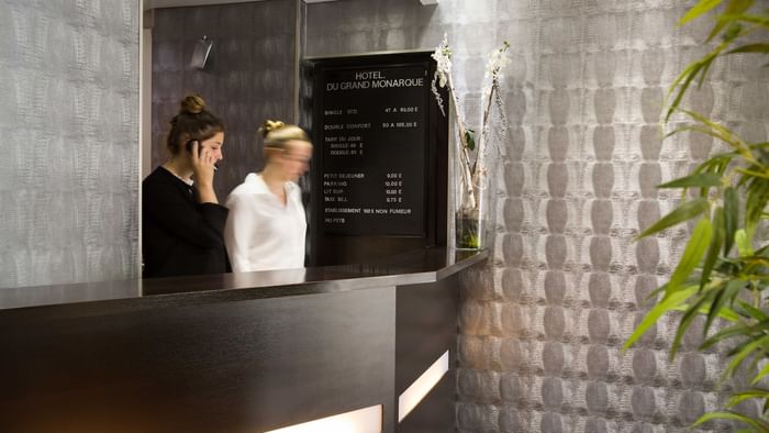 A receptionist at the reception desk in du Grand Monarque