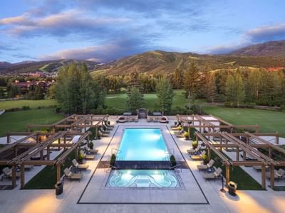 Hotel Park City Autograph Collection pool lined with lounge chairs and pergolas surrounded by greenery