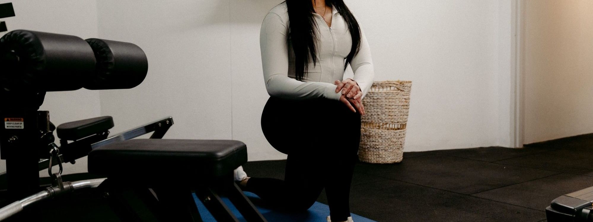Woman doing squats on yoga mat near exercise equipment in Novotel Sydney Parramatta's gym.