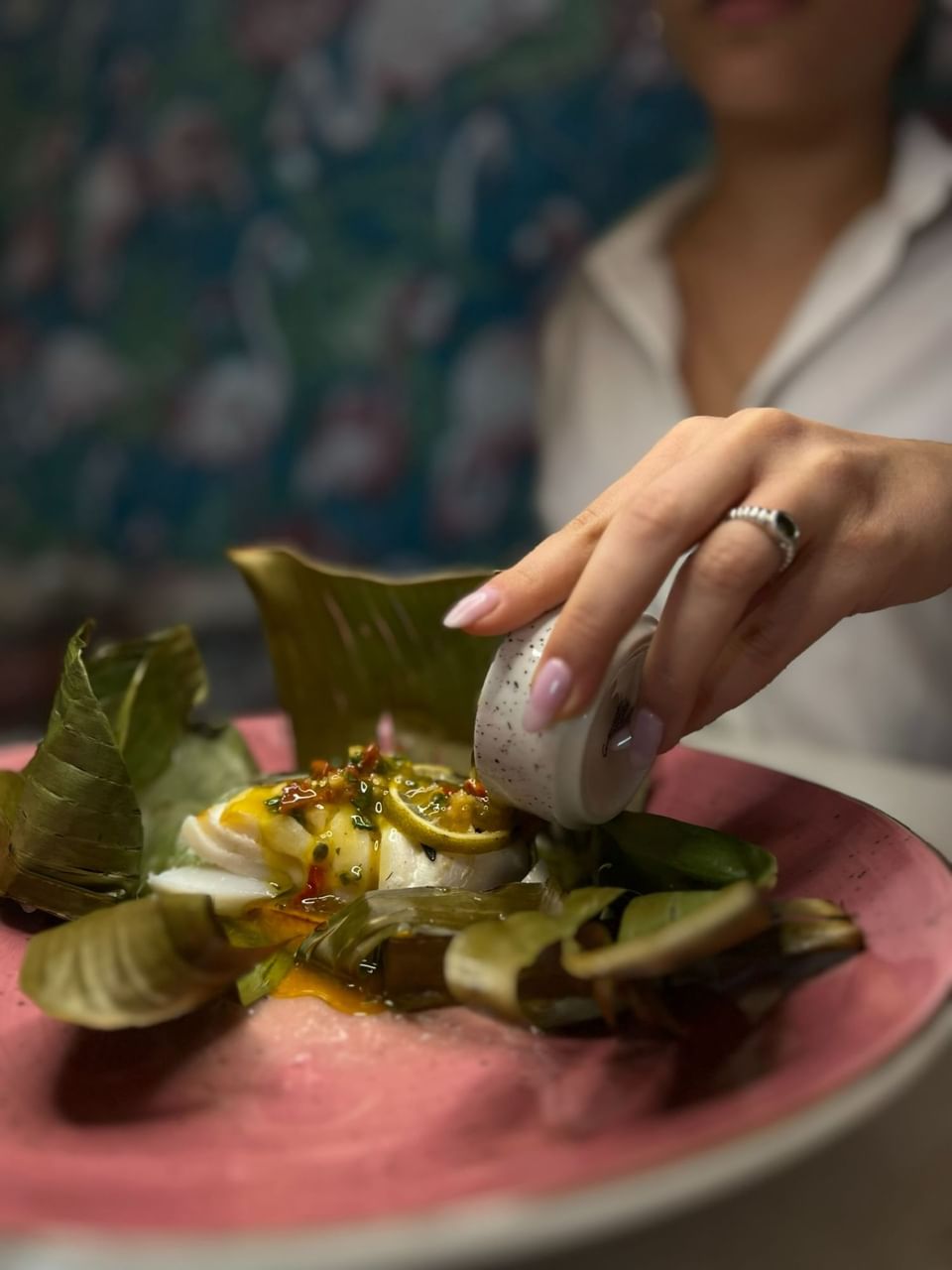 A lady pouring special sauce to dish at Muze Lounge & Terrasse