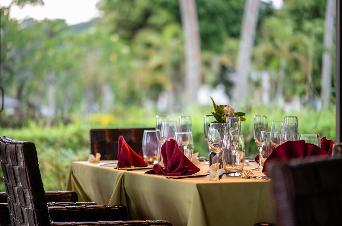Dining table set with red napkins & wine glasses, and floral accents in Wild Ginger Restaurant at warwick le lagon-vanuatu