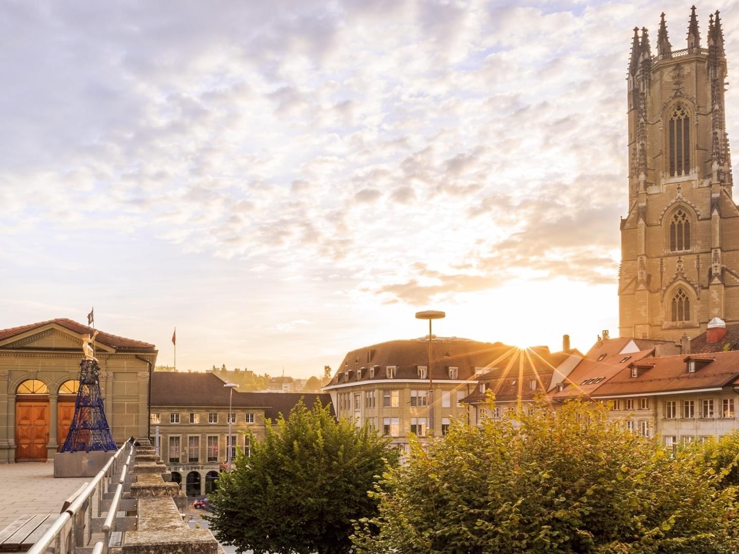 Sunrise over a historic cityscape featuring Fribourg Cathedral near Hotel des Innovations