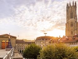 Sunrise over a historic cityscape featuring Fribourg Cathedral near Hotel des Innovations