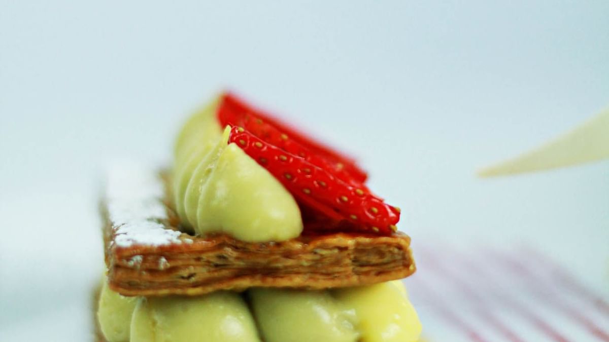 Deux gâteaux avec crème jaune et fraises sur assiette blanche avec décoration rouge et jaune.
