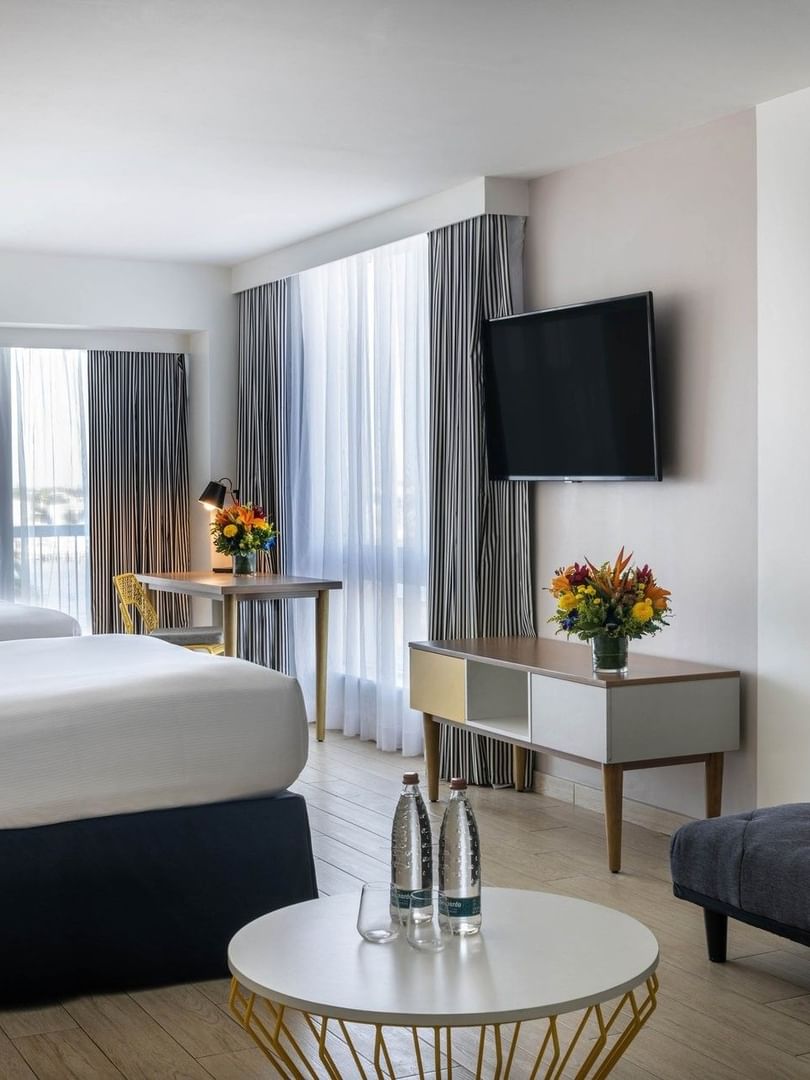 Island View featuring twin beds by a gray sofa and a white table under a wall TV at Warwick Paradise Island Bahamas