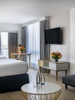 Island View featuring twin beds by a gray sofa and a white table under a wall TV at Warwick Paradise Island Bahamas