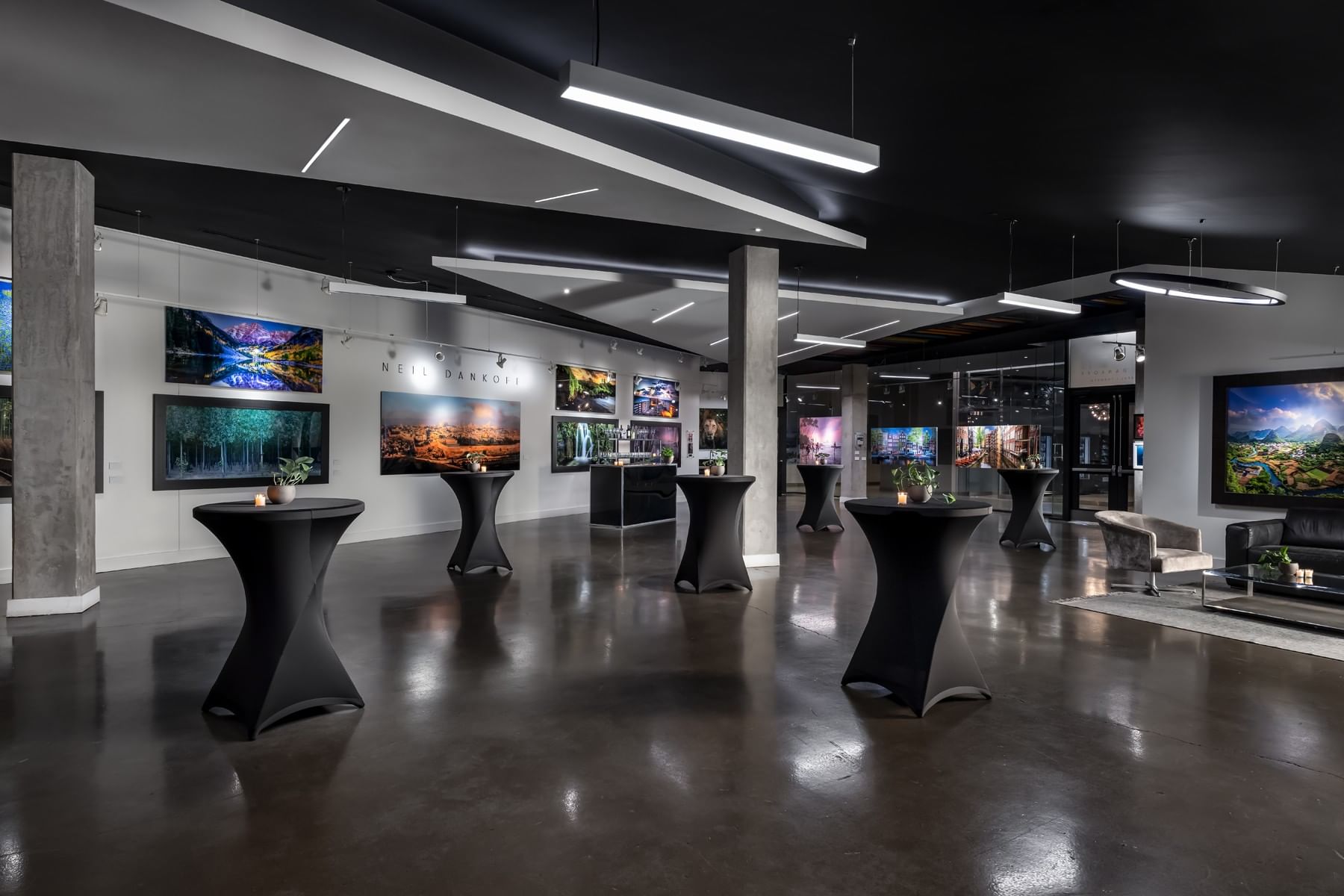 Cocktail tables with candles by framed landscape photography on gallery walls at Hotel X Toronto