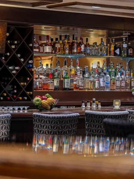 Margaux Lounge Bar featuring rows of liquor bottles by a wine rack under warm lighting at Warwick Seattle