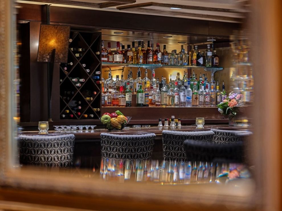 Margaux Lounge Bar featuring rows of liquor bottles by a wine rack under warm lighting at Warwick Seattle