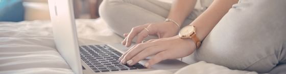 A woman working with a laptop on a bed at Vasa Hotel Surabaya