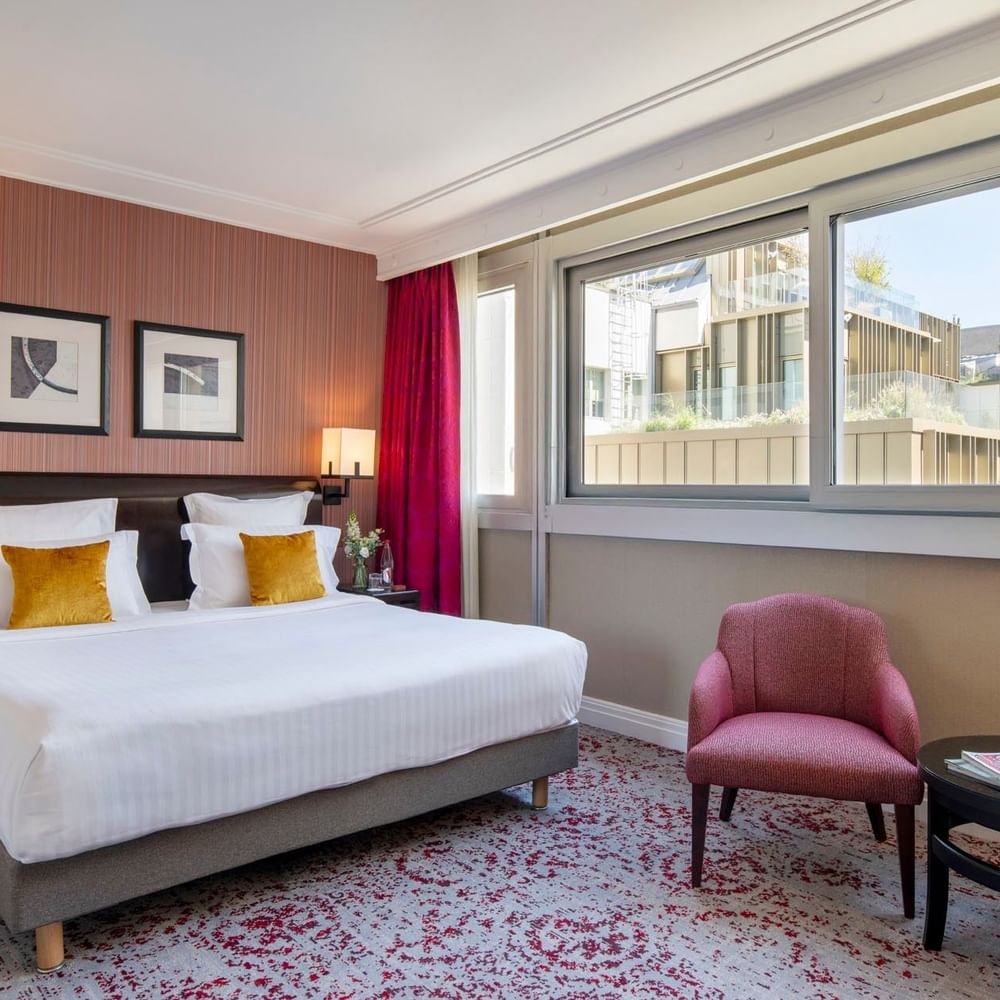 Élégante chambre Deluxe dotée d'un grand lit, d'un coin salon confortable et d'une vue sur la ville au Warwick Champs-Élysées Paris.