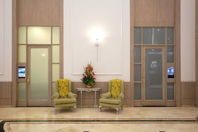 Un lobby con dos sillas y mesa frente a las puertas del Hotel Dann Carlton Medellín