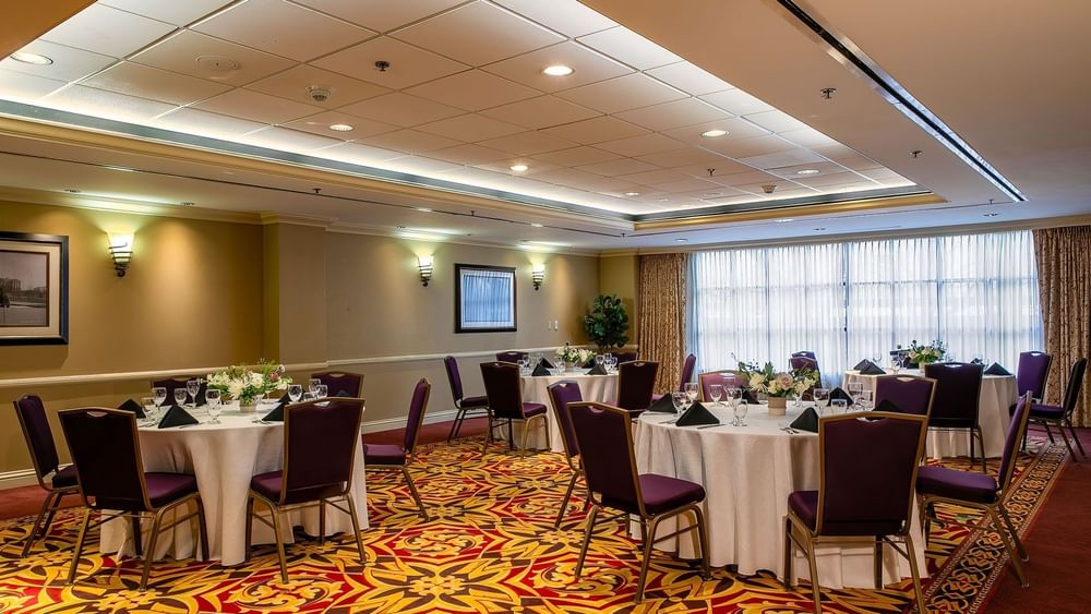 Set tables with purple chairs by patterned carpet under warm wall lights in Capitol III/IV at Warwick Denver