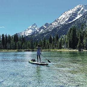 Lady paddle boarding in a Lake with a view near Hotel Jackson