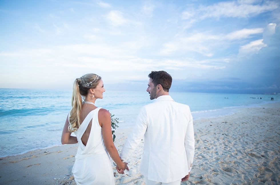 Couple holding hands & walking on beach near Live Aqua Resorts and Residence Club