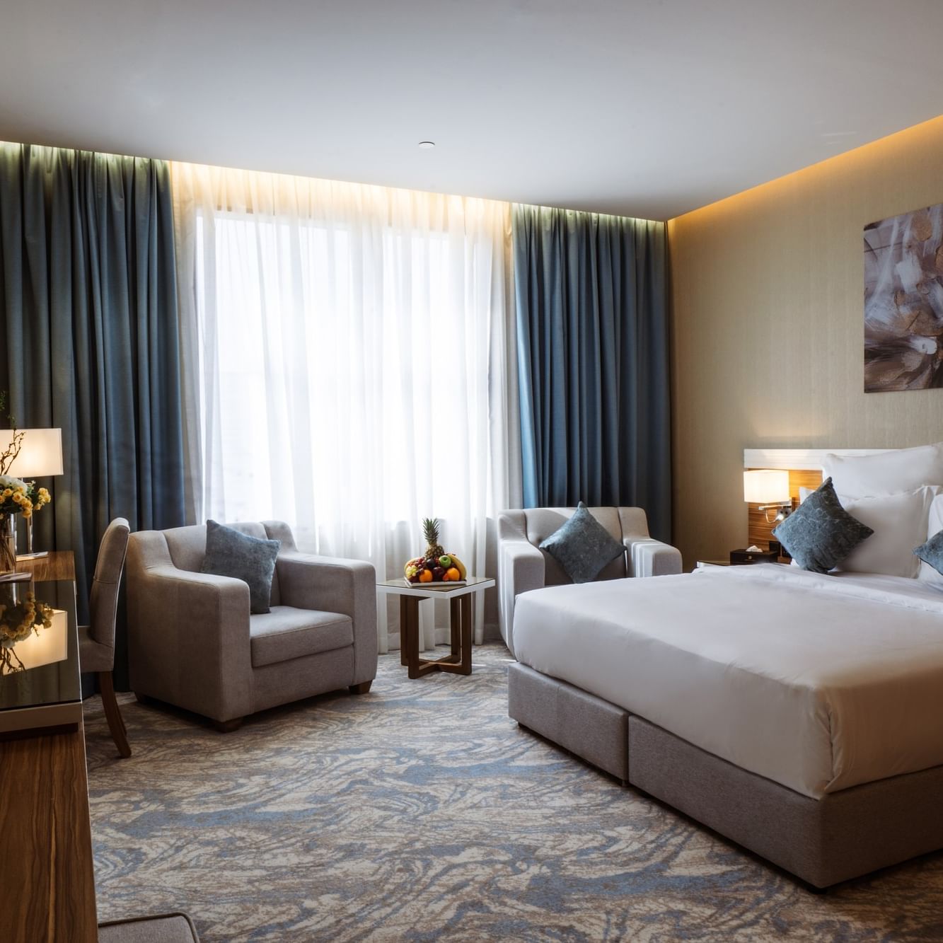 Chambre d'hôtel élégante avec un grand lit, deux chaises et une table au Cantonal Hotel by Warwick Riyad.