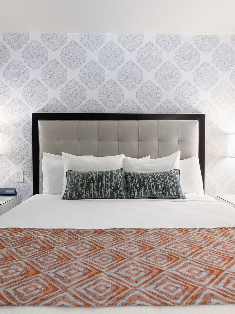 Bed between the side table against the patterned wall in the Premier Suite at Warwick New York