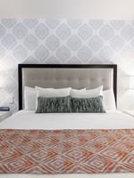 Bed between the side table against the patterned wall in the Premier Suite at Warwick New York