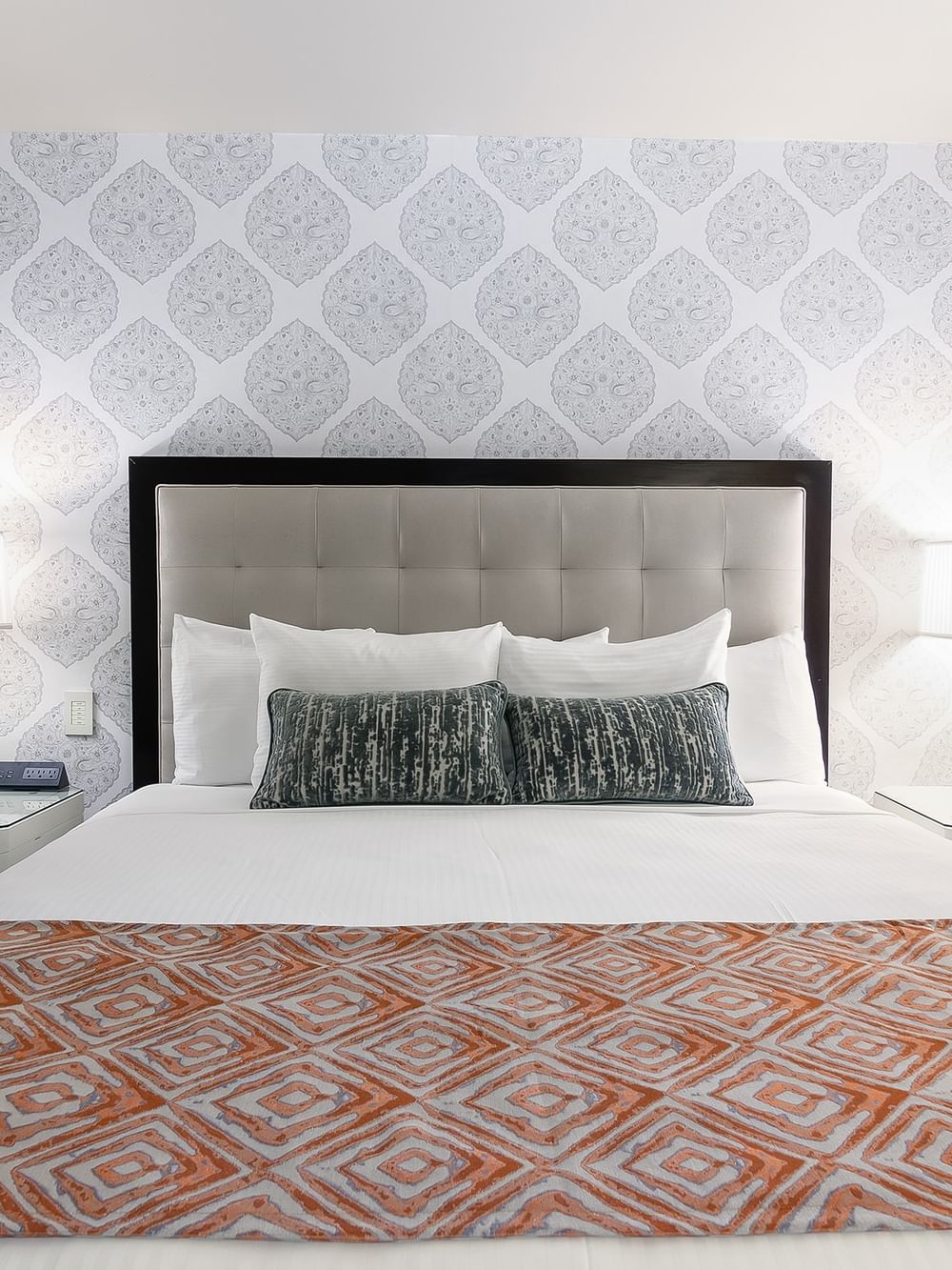 Bed between the side table against the patterned wall in the Premier Suite at Warwick New York