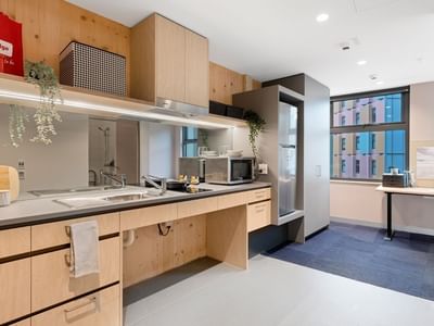 Modern kitchen with wooden cabinets, appliances, and large window in La Trobe University apartments.