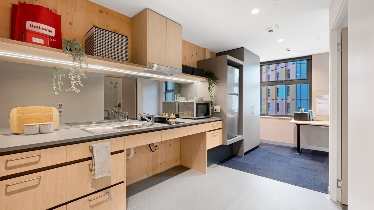 Modern kitchen with wooden cabinets, appliances, and large window in La Trobe University apartments.