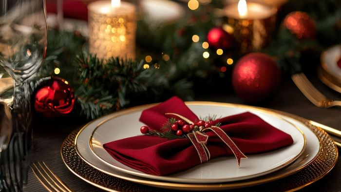 Plates, napkins, and utensils set on a table with a festive christmas arrangement for Jeff's Cellar Christmas Dinner
