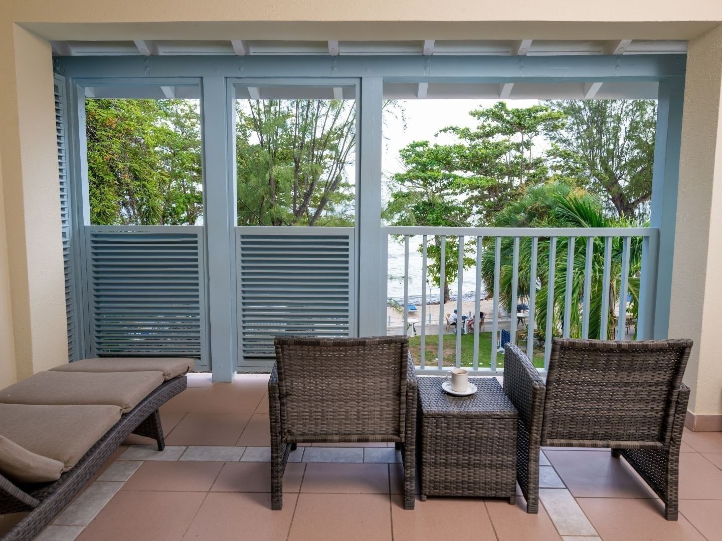 Two wicker chairs and a table with a cup on balcony at Savannah Beach Hotel.