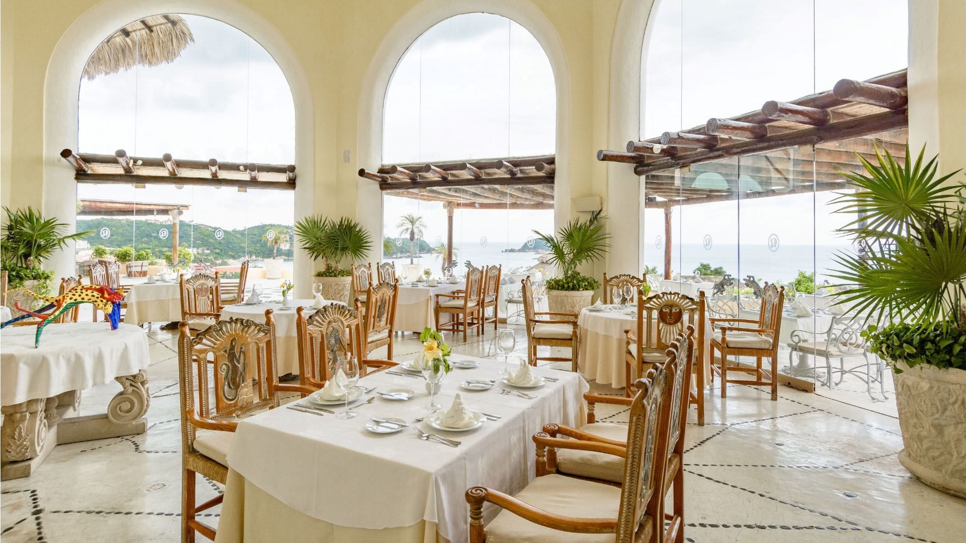 Sunlit Las Cupulas Restaurant featuring white linens and views of the tropical coast at Quinta Real Huatulco
