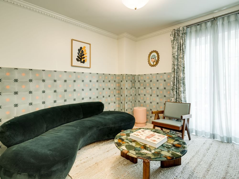 A stylish living room with a green sofa, marble coffee table, and patterned wallpaper.