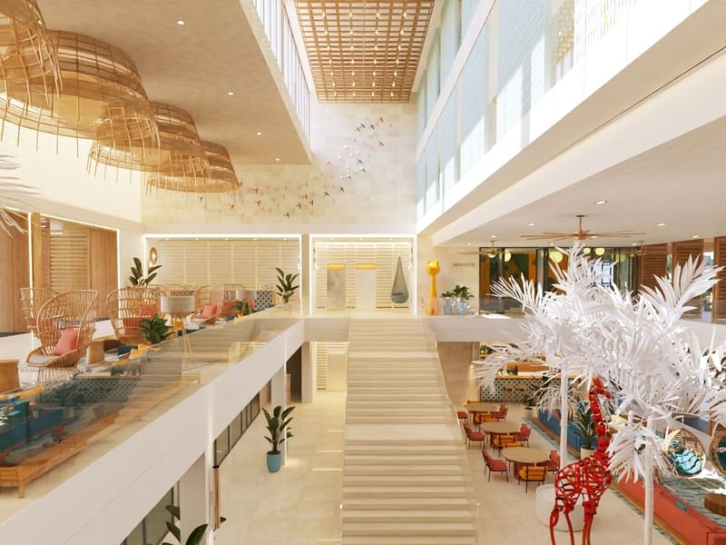Gran atrio de varios niveles en Fiesta Americana Funeeq Punta Cana con decoración de palmeras blancas y sillones elegantes