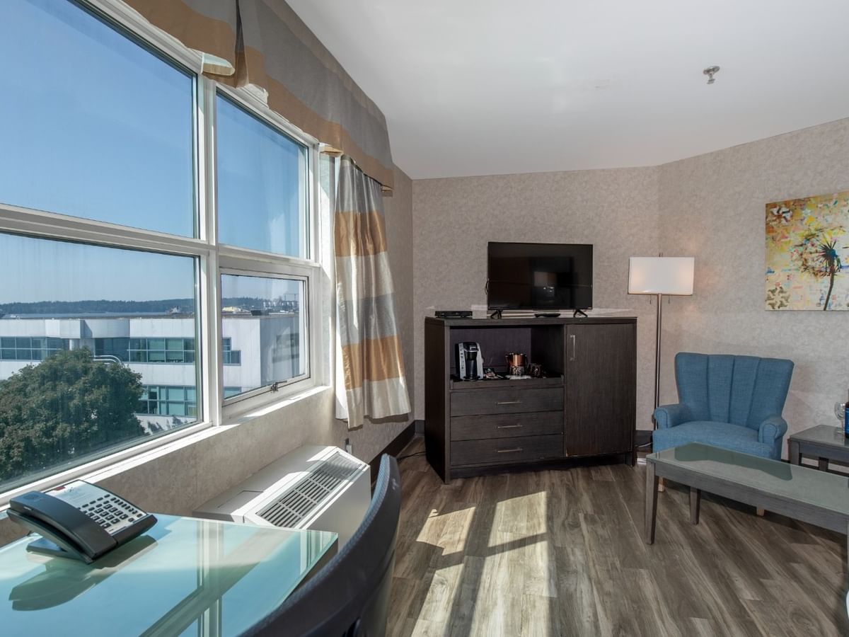 Coast Premium King with large windows, two blue chairs, TV, and a painting at Coast Lonsdale Quay Hotel