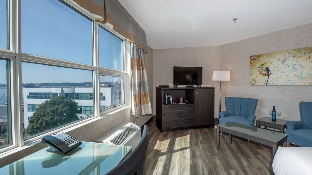 Coast Premium King with large windows, two blue chairs, TV, and a painting at Coast Lonsdale Quay Hotel