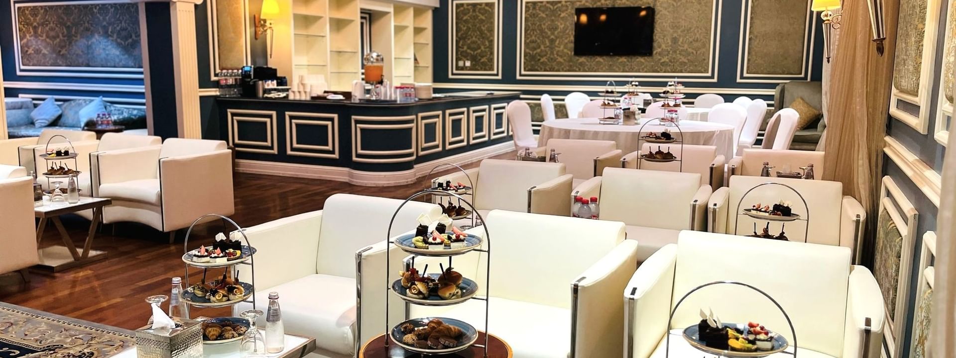 Elegantly decorated Blue Room event space with white furniture and food displays at Warwick Doha