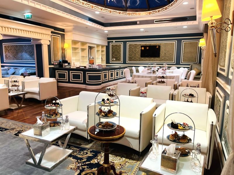 Elegantly decorated Blue Room event space with white furniture and food displays at Warwick Doha.