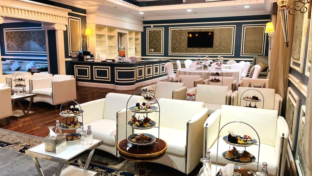 Elegantly decorated Blue Room event space with white furniture and food displays at Warwick Doha.