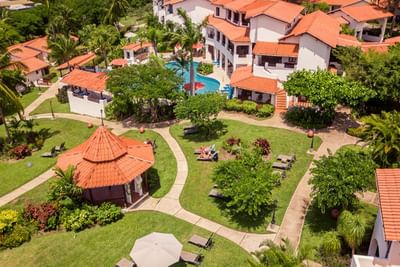 Aerial view of resort buildings with a swimming pool and tropical trees around them at Sugar Cane Club Hotel & Spa
