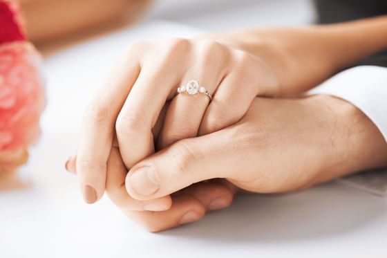 Close-up of intertwined hands with an engagement ring at Carlton Hotel Singapore