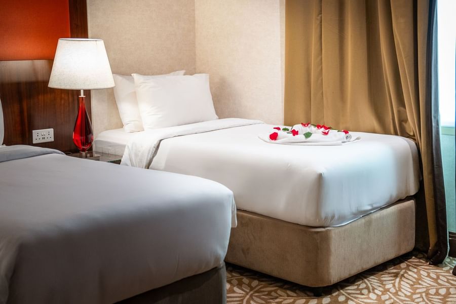 Twin bedroom setup with floral petal decor, and warm bedside lamp at Saja by Warwick Makkah