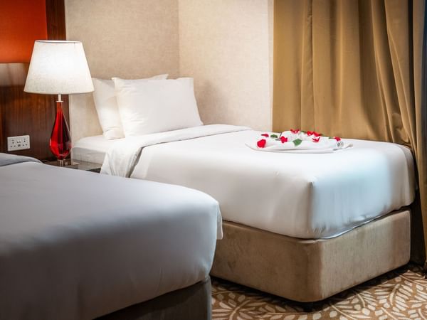 Two beds with floral decor and a bedside lamp at Saja by Warwick Makkah.