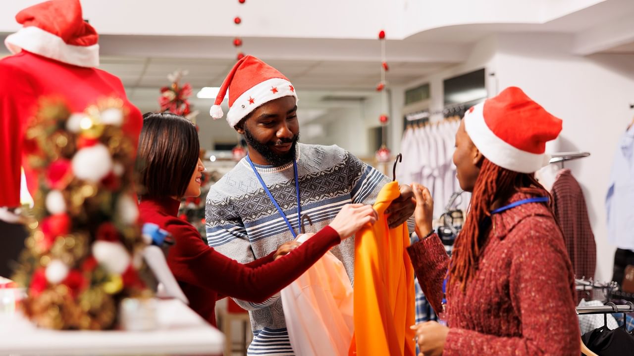 Holiday shoppers receiving help from retail staff in Santa hats