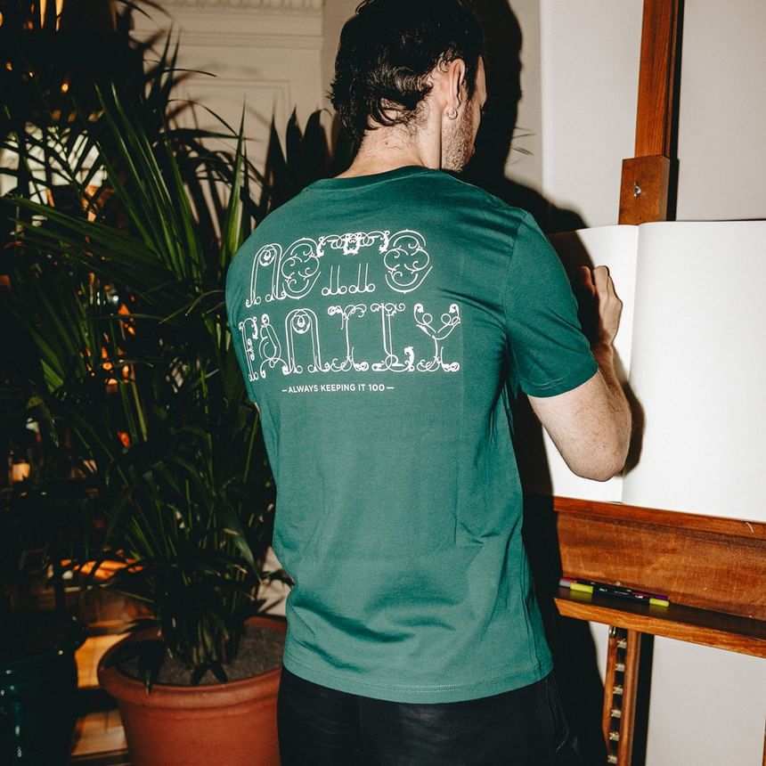 Mann trägt ein grünes T-Shirt mit Motto-Logo auf der Rückseite bei Hotel Motto