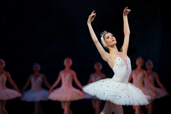 Ballerina in a tutu dances by her troupe under dramatic stage spotlights near Paramount Hotel Seattle