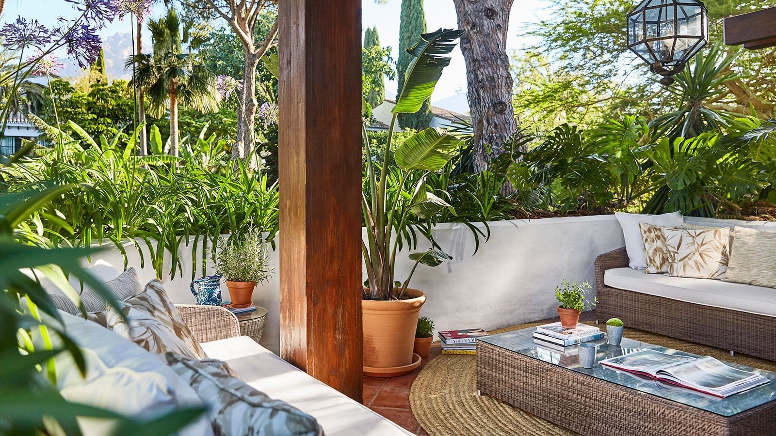La Concha Suite terrace with comfortable wicker furniture, rich wood columns, and potted plants at Marbella Club