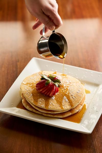 Pouring honey on pancakes at The IowaStater Restaurant