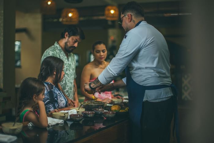 Chef demonstrating cooking techniques to family guests during an interactive culinary class at Los Altos Resort