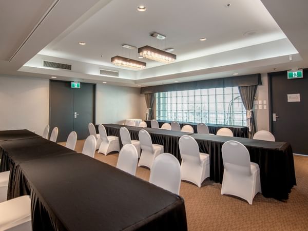 Conference room with long tables, white chairs and windows