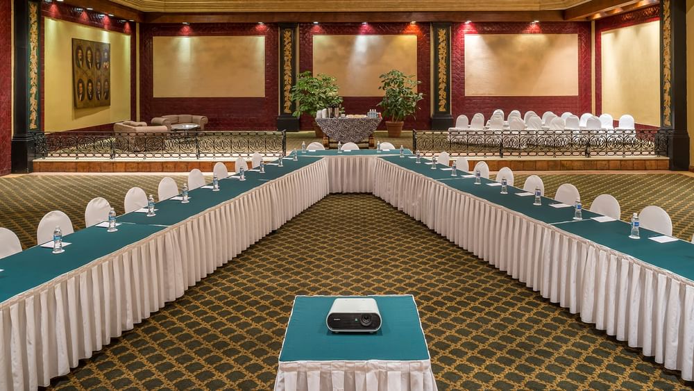 Salón San Marcos featuring a projector, white chairs, and a patterned rug at Quinta Real Aguascalientes